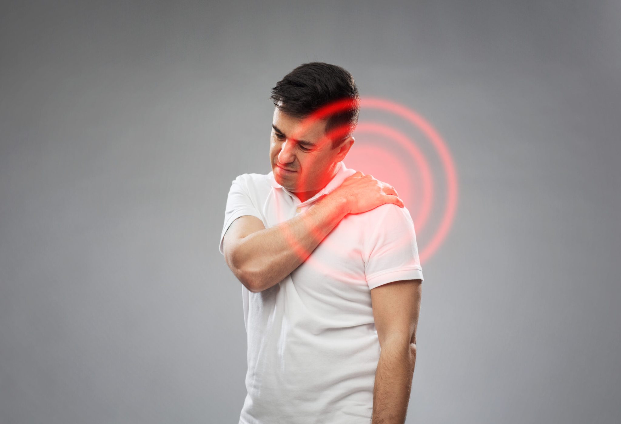 people, healthcare and problem concept - unhappy man suffering from pain in shoulder over gray background